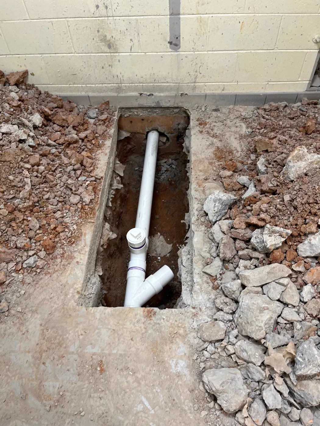 New plumbing lines run through an open floor trench during a commercial venue renovation, Metro Atlanta