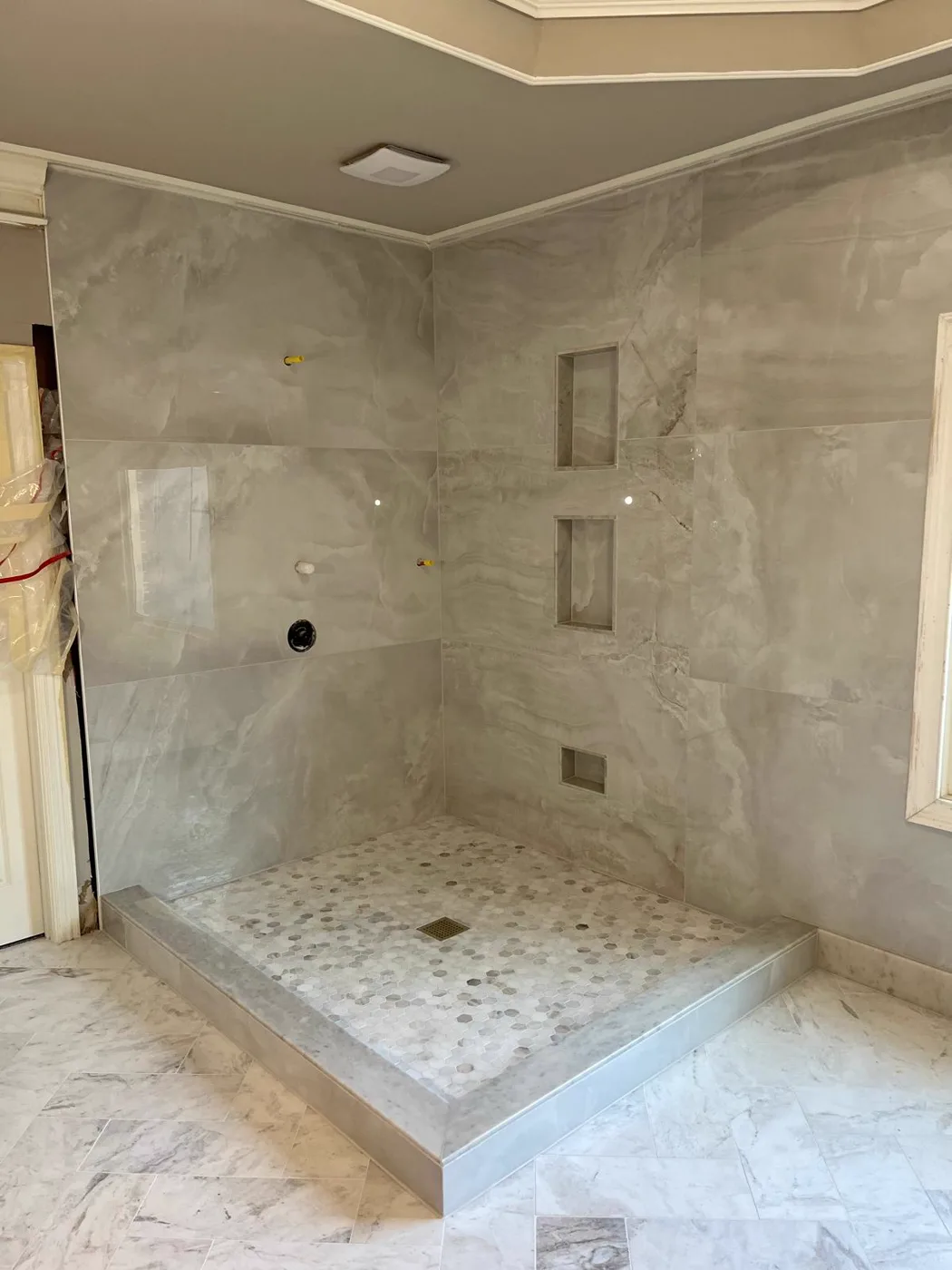 Ducha tipo spa terminada con paredes de mármol, nicho revestido de azulejo y piso de piedra, renovación de un local comercial, Metro Atlanta