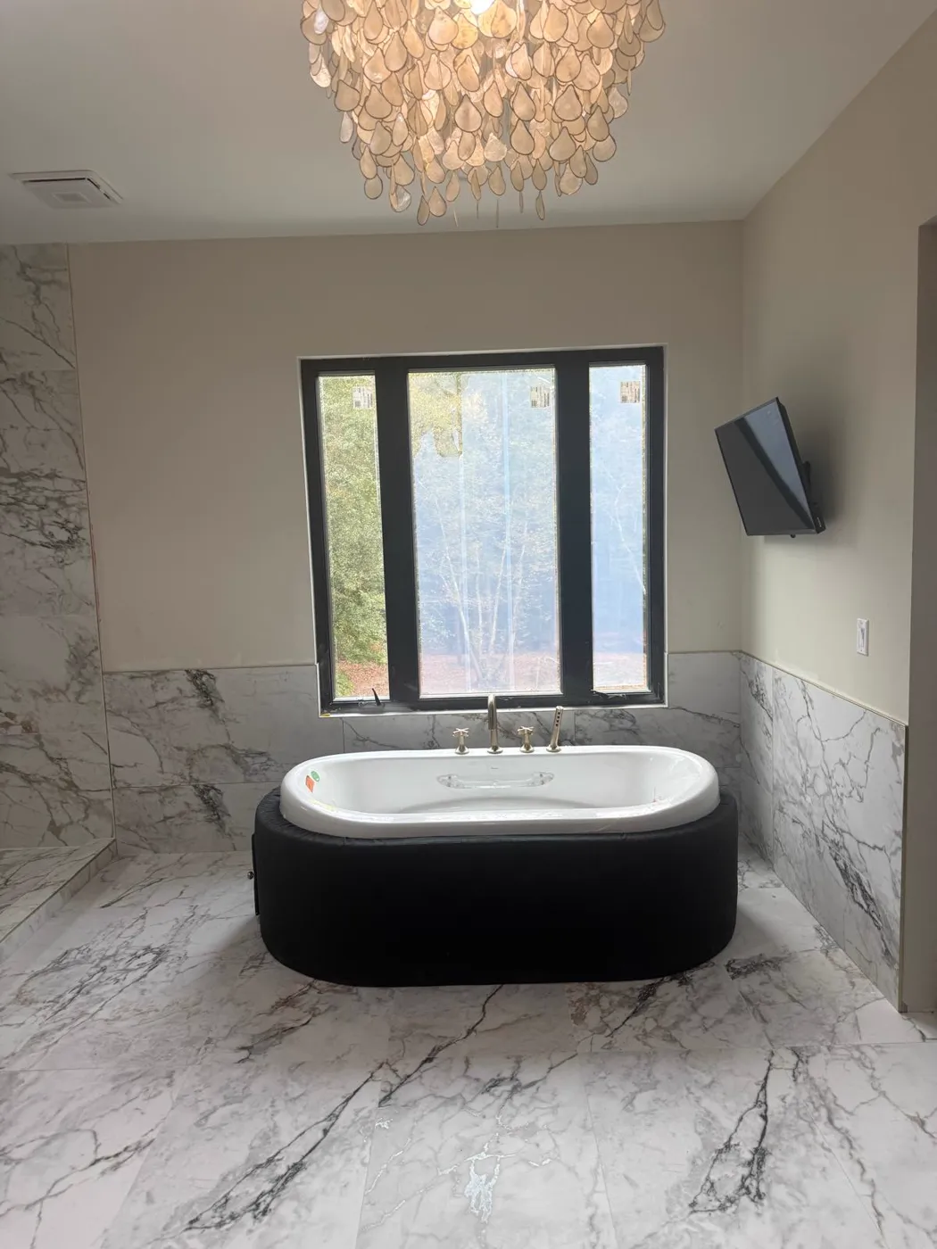 Baño principal terminado con bañera exenta, paredes en azulejo tipo mármol y candelabro, Metro Atlanta