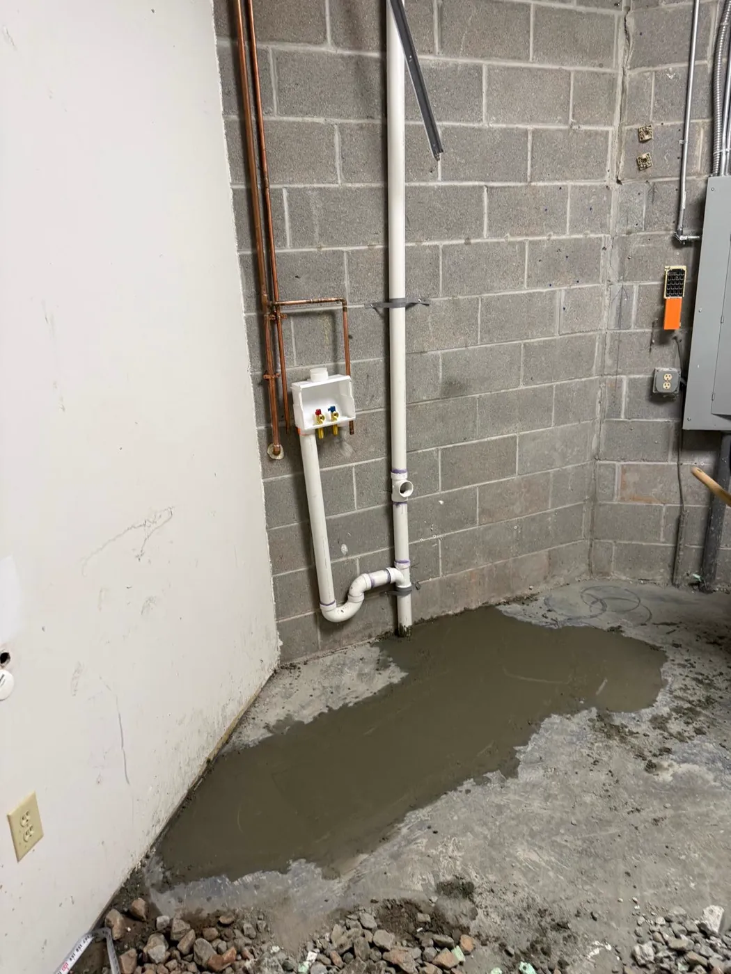 Basement plumbing with copper supply lines, a washer box and a fresh concrete patch, Metro Atlanta